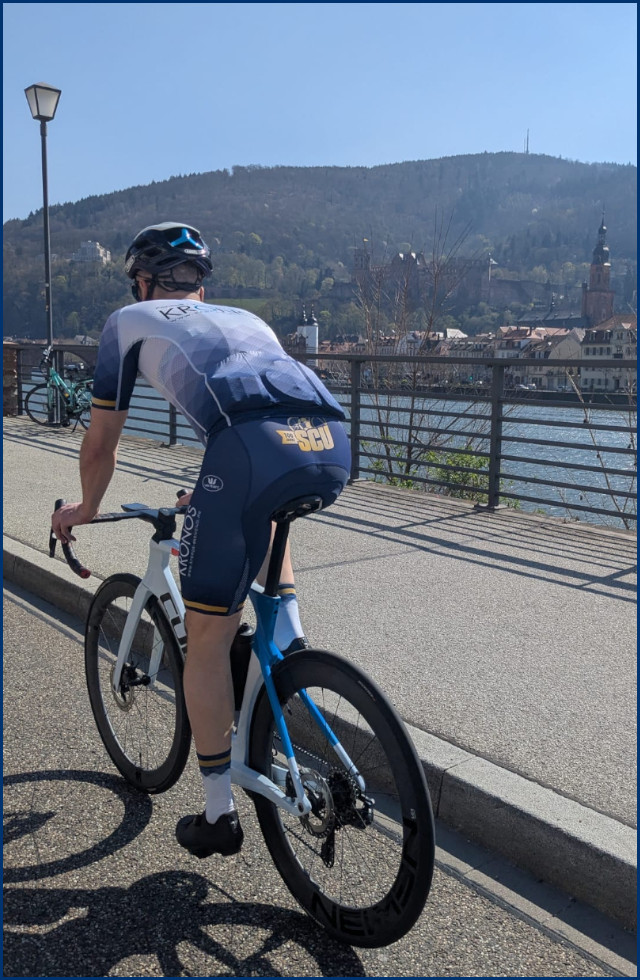 Rennradfahrer am Neckar mit Schloss Heidelberg im Hintergrund