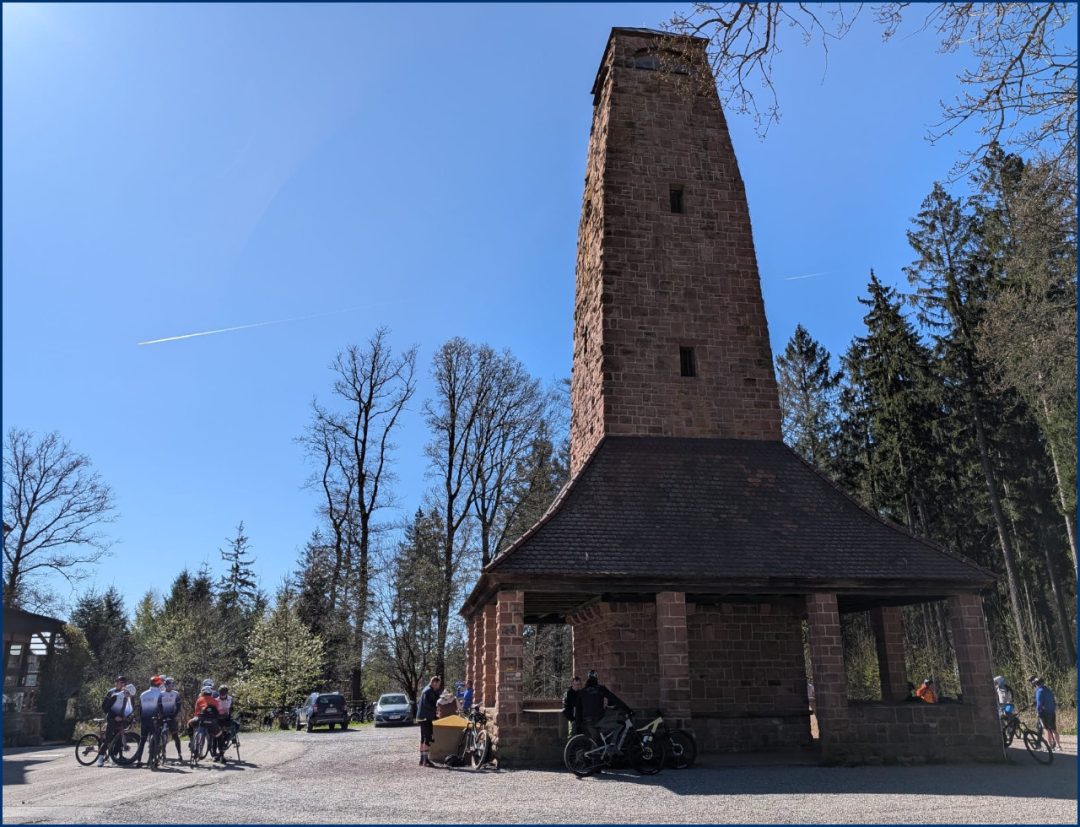 Rennradgruppe neben einem Turm am Gipfel des Berges Weißer Stein